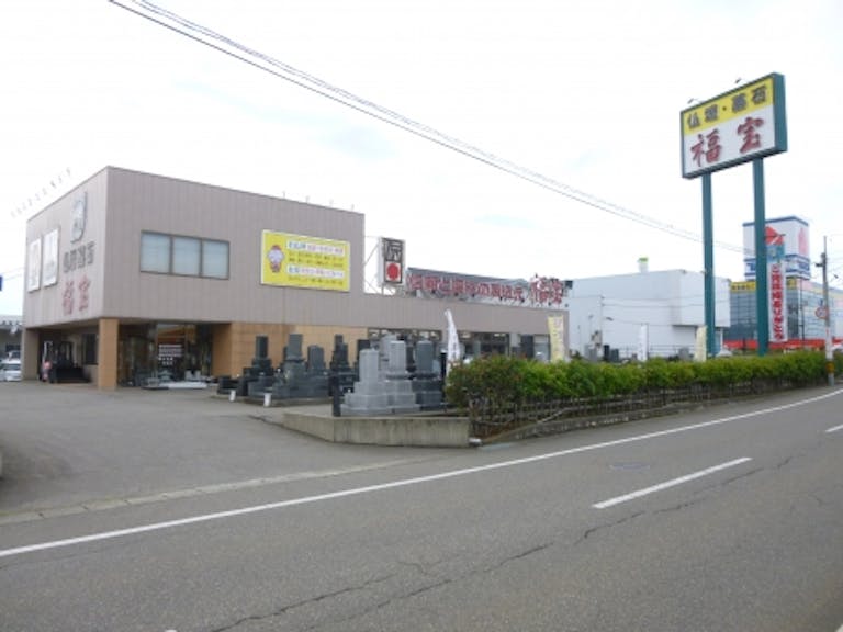 広い墓石展示場が目印の国道８号線沿いにある店舗外観