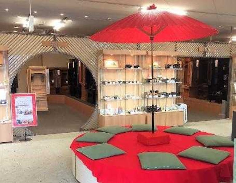 緋もうせんの敷かれた丸いベンチと赤い傘の休憩コーナー